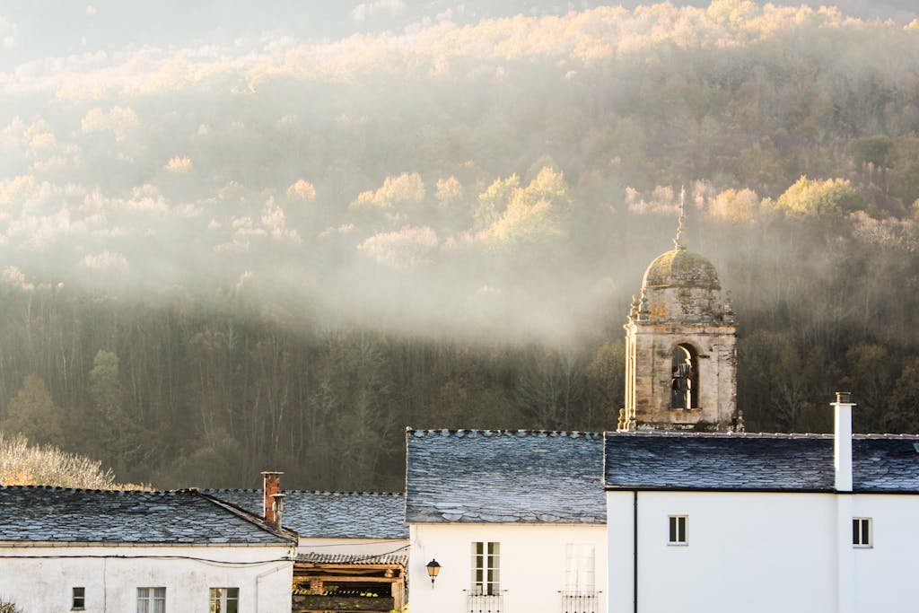 Bell Tower of a Medieval Church Above the Blue Roofs of the Village at the Foot of the Mountain